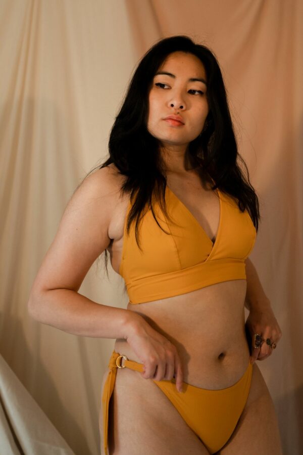 Femme debout portant un maillot de bain jaune emboitant de la marque maison finou